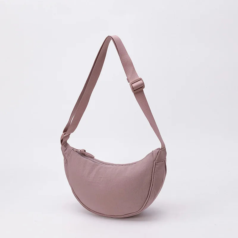 حقيبة كروسية من النايلون بلون الموف الفاتح مع حزام كتف على خلفية بيضاء.