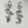A pair of handmade lily of the valley flower keychains featuring a pink to blue gradient with green and purple leaves.