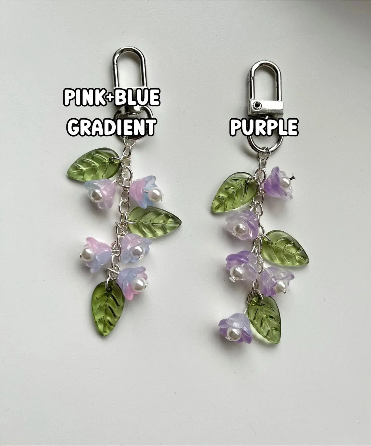 A pair of handmade lily of the valley flower keychains featuring a pink to blue gradient with green and purple leaves.