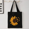 Black canvas tote bag featuring a yellow sunflower print with small yellow butterflies.