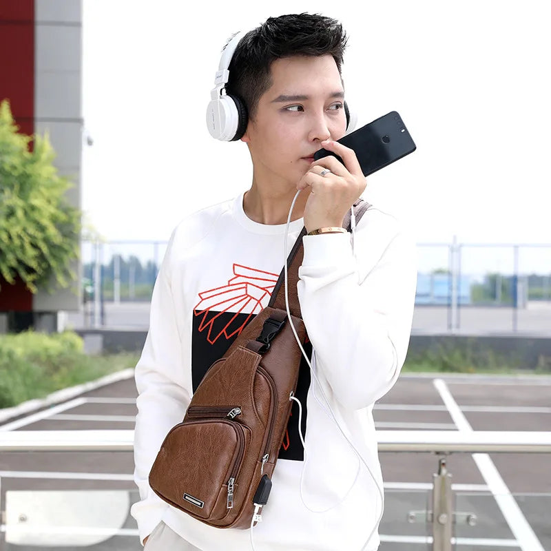 A young man wearing a white sweatshirt and carrying a brown chest bag with a headphone port, looking to the side.