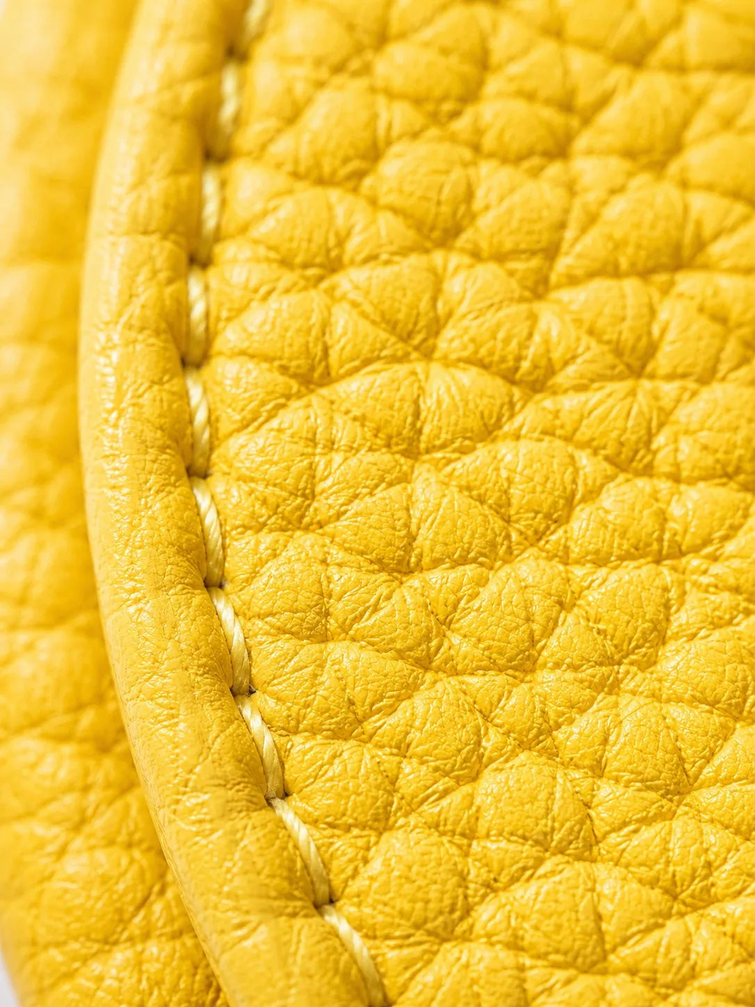 Close-up of a yellow fruit-shaped PU leather coin purse keychain with visible stitching.