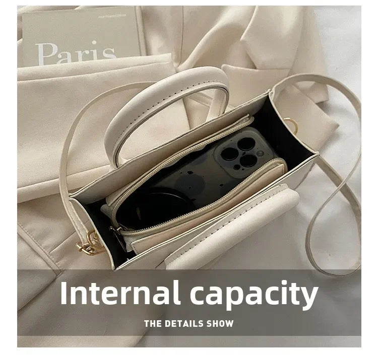 Vue rapprochée d'un sac à main en cuir crème avec poignée supérieure, montrant la capacité intérieure.
