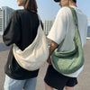 A person is holding a beige corduroy casual crossbody shoulder bag against a gray background.