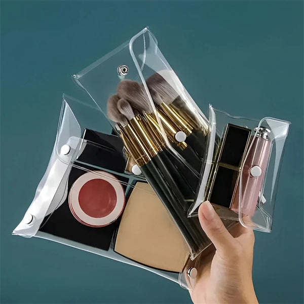 A hand holds a transparent portable organizer pouch containing makeup brushes and cosmetic tools.