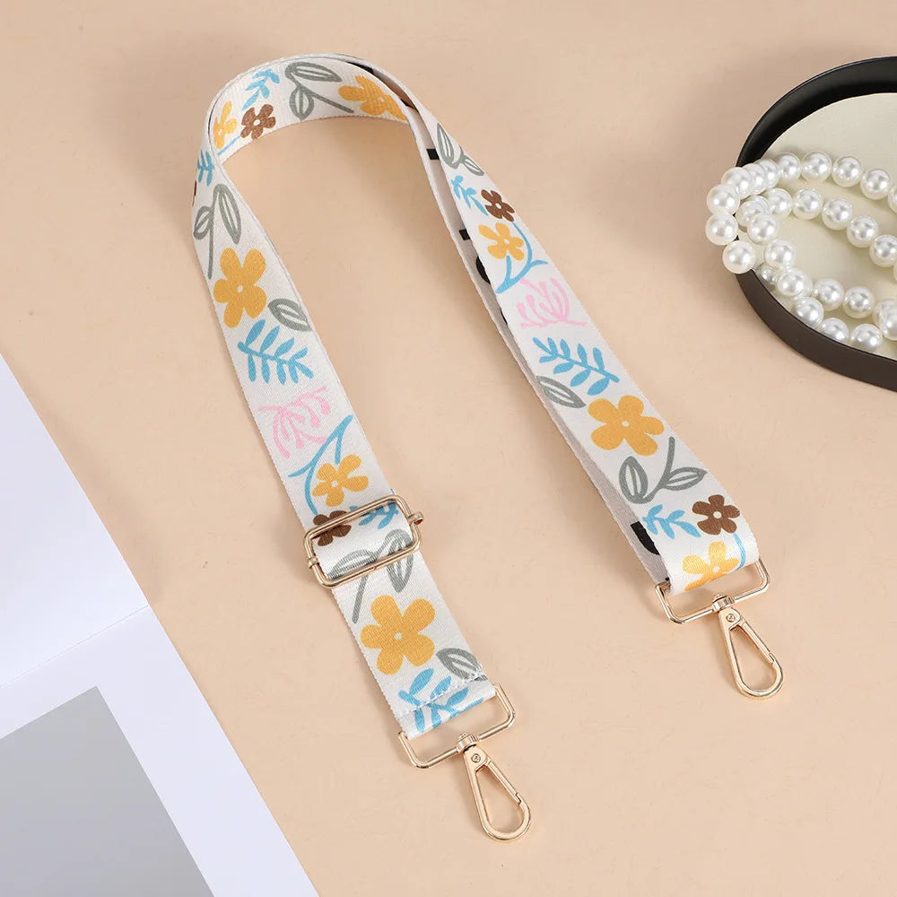 A beige and floral patterned nylon crossbody bag strap with a metal buckle is displayed on a light background.