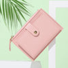 A pink PU leather mini card holder wallet is shown diagonally against a light green background.