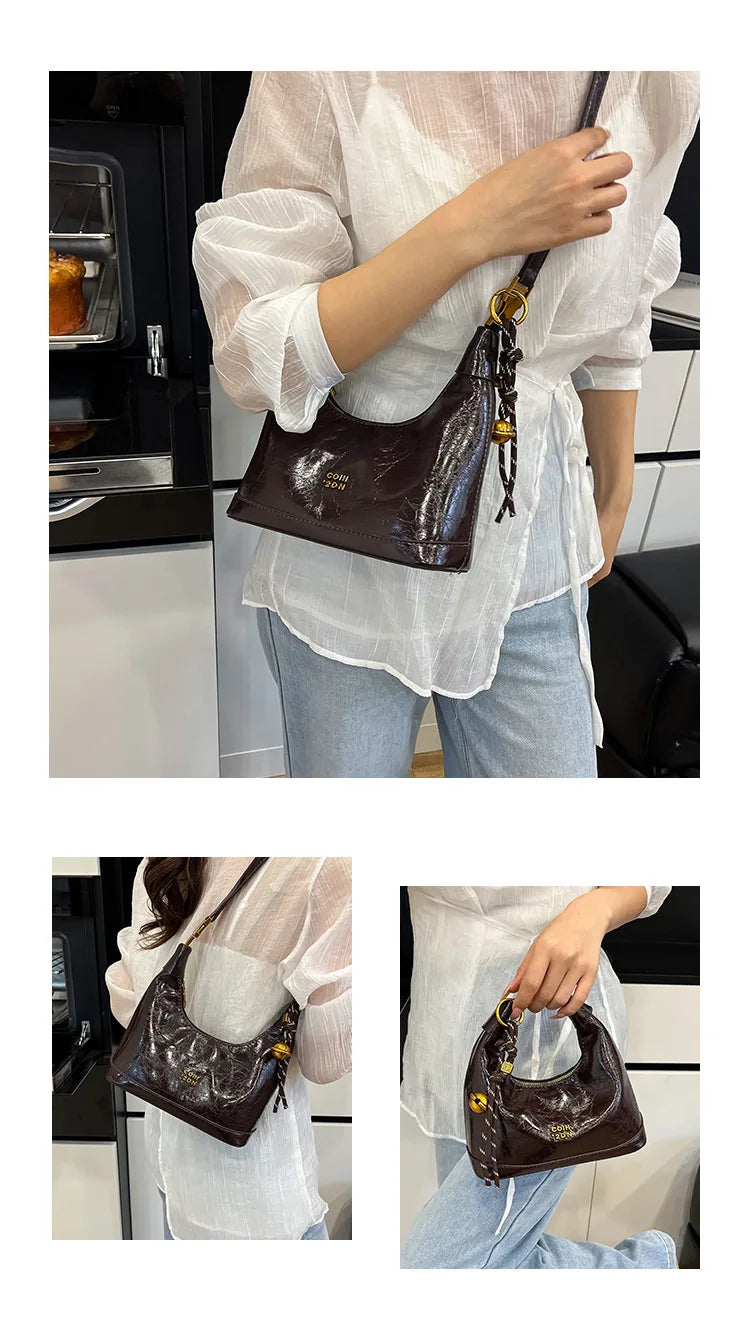 A woman holds a brown retro PU leather shoulder bag against a white blouse and light blue jeans.