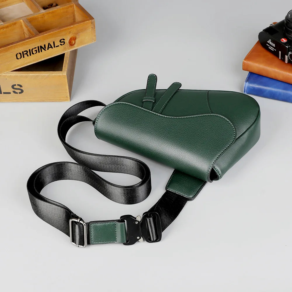 A dark green men's solid color chest bag with black strap lying on a white surface.