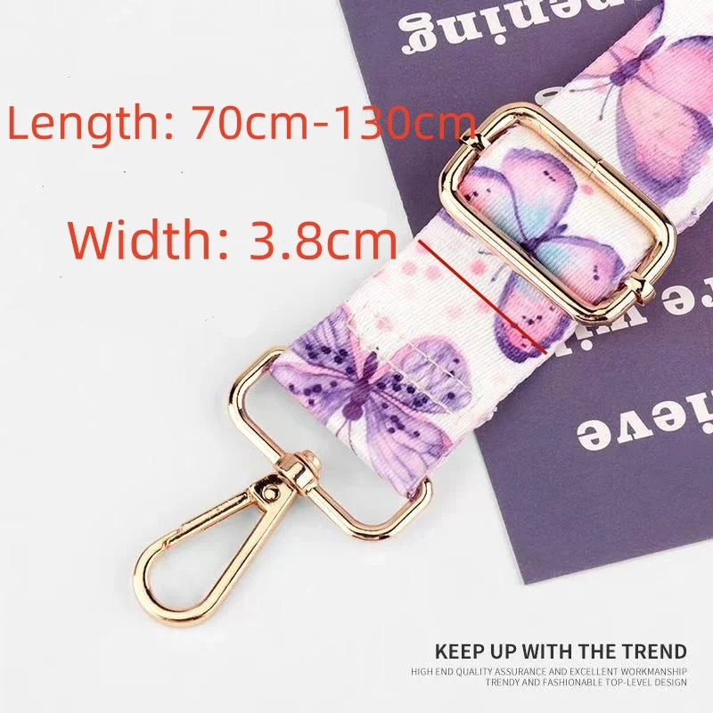 A close-up of a pink and purple floral patterned nylon bag strap with a gold-toned buckle and lobster clasp.
