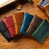 A collection of five minimalist full-grain leather passport holders and card wallets in various shades of brown, green, and r