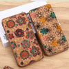 A brown wood-grain leather wallet decorated with floral patterns and used as a card holder.