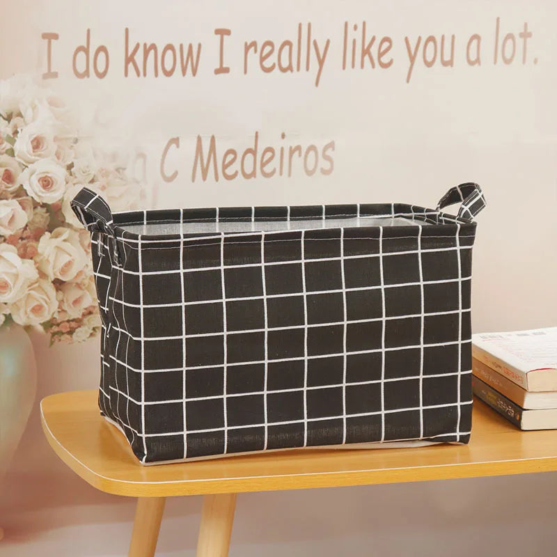 A black checkered fabric storage basket with handles sits on a wooden shelf next to a sign.