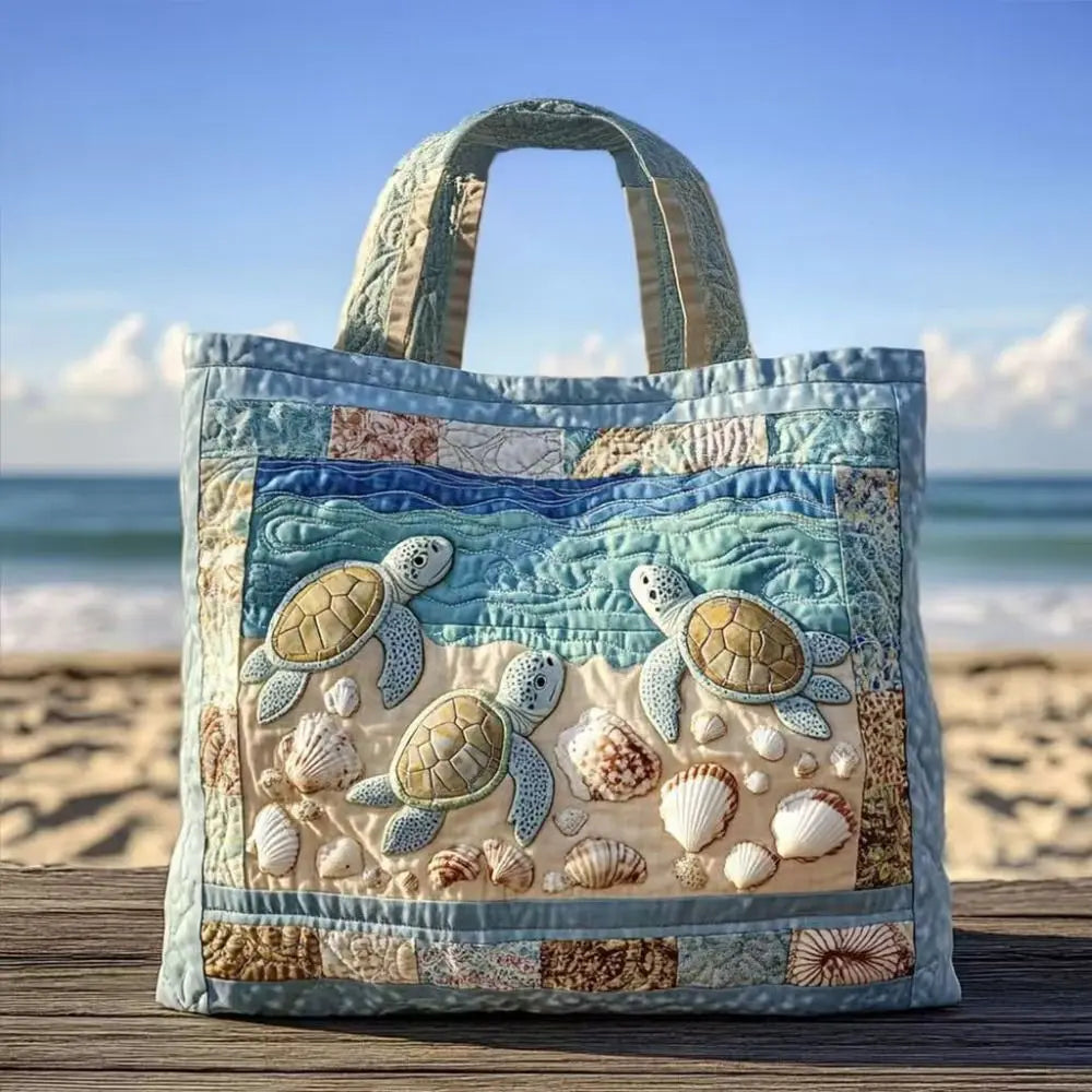 A quilted canvas tote bag featuring embroidered sea turtles in shades of blue, green, and beige.