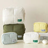 Aesthetic quilted puffer makeup bags in white, olive green, and pale yellow.