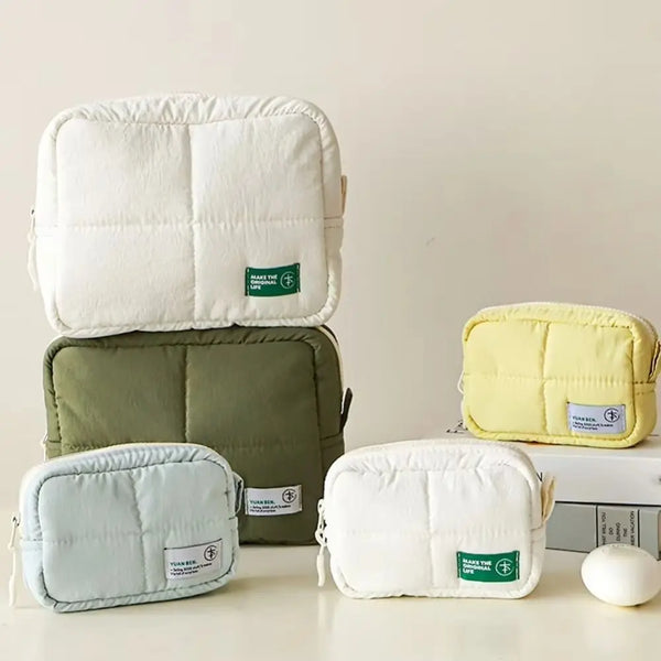 Aesthetic quilted puffer makeup bags in white, olive green, and pale yellow.