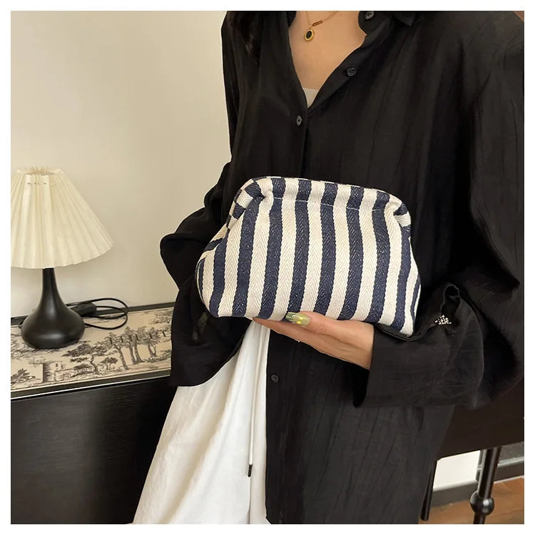 A woman holds a striped summer crochet handbag against a black shirt.