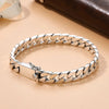 A silver punk charm bracelet featuring a chain design and a padlock clasp, displayed on a light beige surface.
