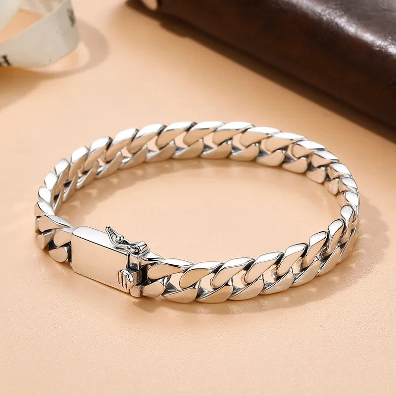 A silver punk charm bracelet featuring a chain design and a padlock clasp, displayed on a light beige surface.