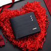 Cartera negra para hombre de PU con múltiples compartimentos sobre un fondo de papel rojo desgarrado.