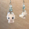 A white fluffy cartoon pendant of Toothless with blue gemstone accents on a silver chain.