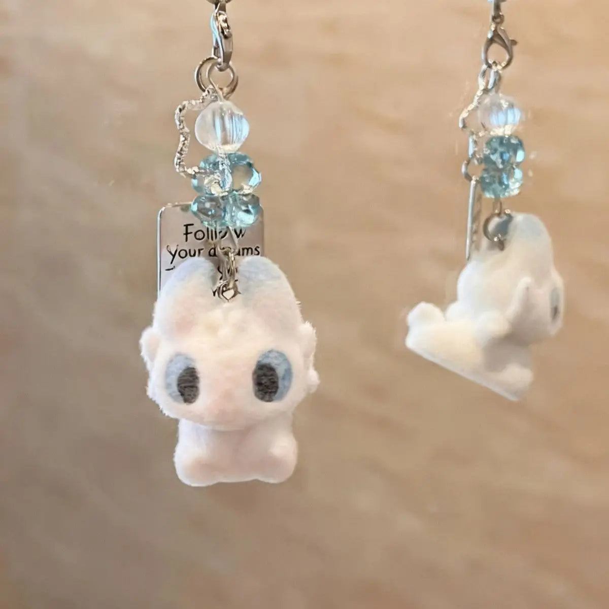 A white fluffy cartoon pendant of Toothless with blue gemstone accents on a silver chain.