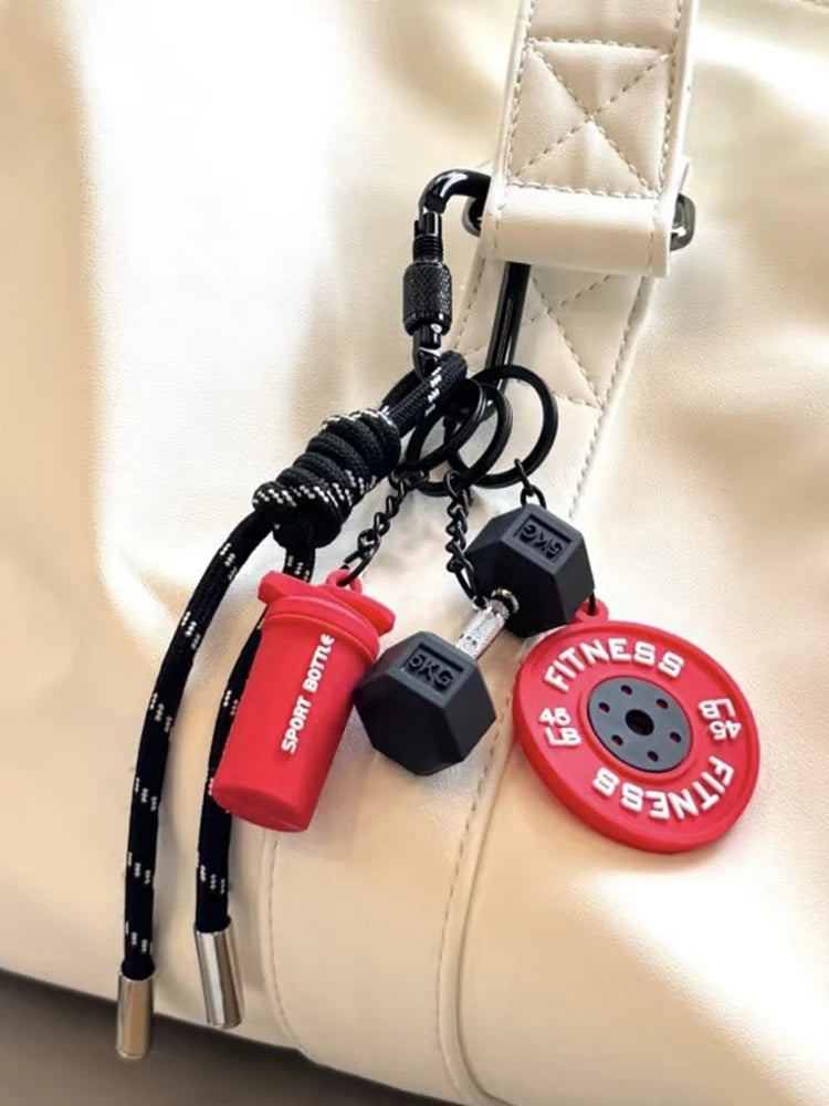 A red fitness keychain with a black D-shape nylon strap and a small black weight attached to a white leather bag.