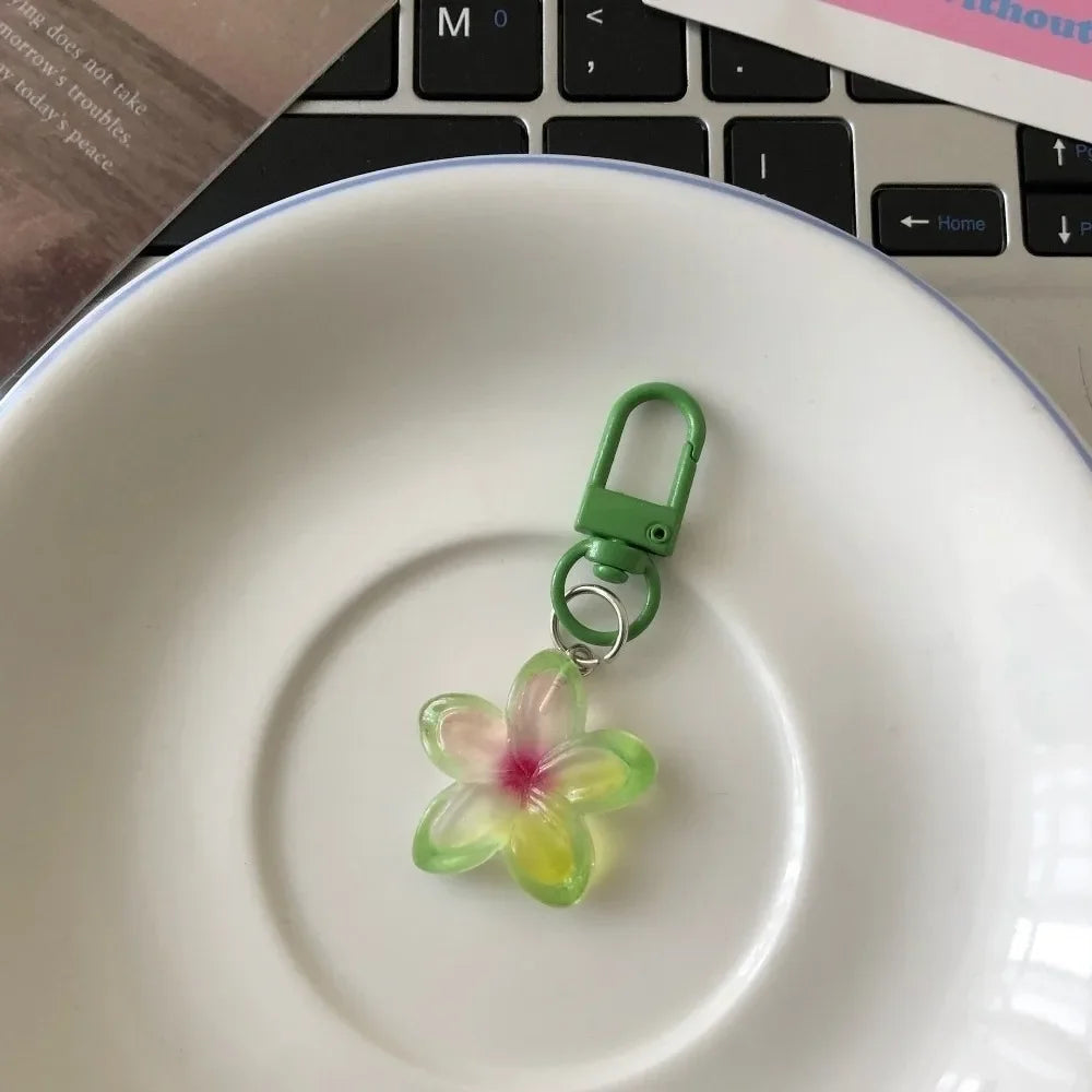 A small, translucent green and yellow resin flower keychain attached to a metal loop, resting on a white plate.