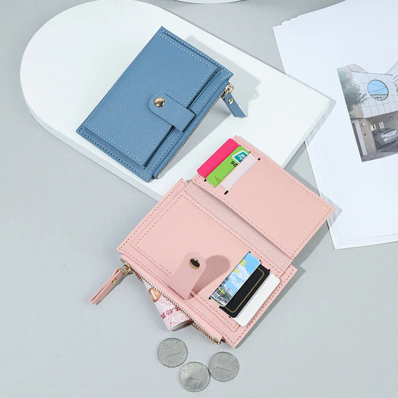 A pink leather card holder wallet and a blue leather card holder wallet are displayed on a white surface.