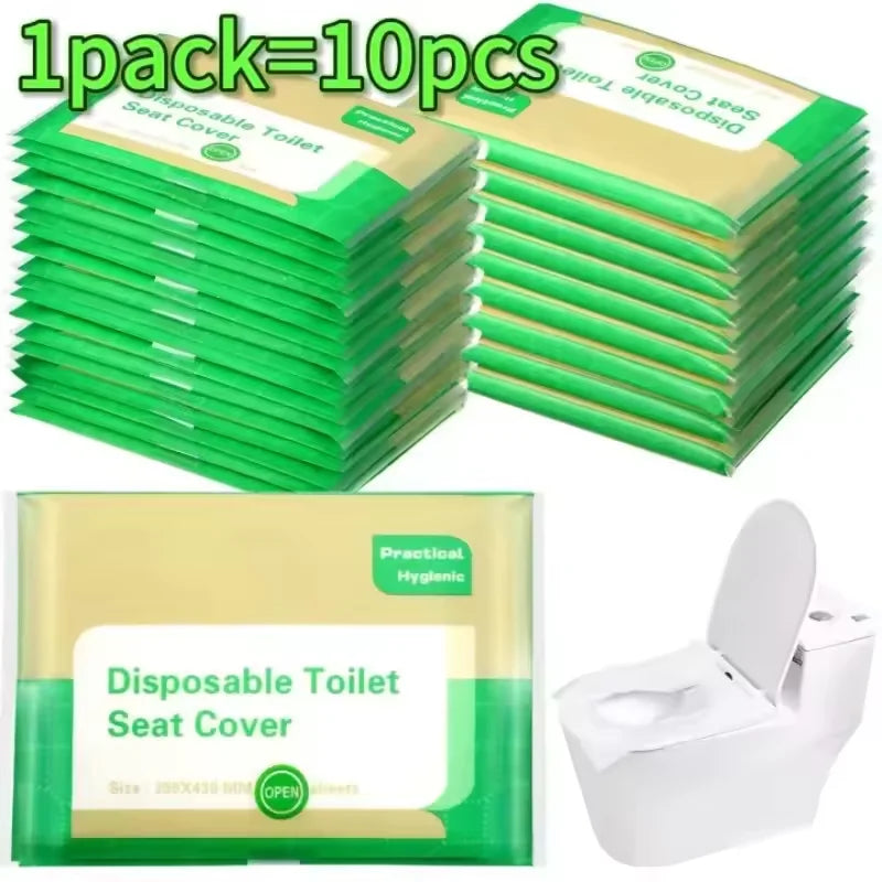 A stack of ten disposable green toilet seat covers next to a single yellow disposable toilet seat cover and an open white toi
