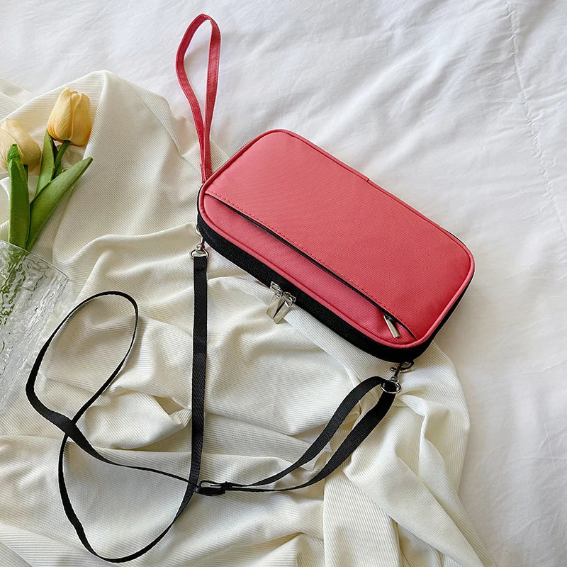 A pink leather multi-pocket travel document organizer with a black strap is laid on white fabric.