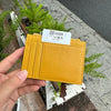 A hand holds a yellow genuine leather zipper card holder with an identification tag.