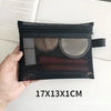 A black mesh cosmetic storage pouch with a clear window showing makeup products is held in a hand.