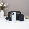Eine schwarze gesteppte Crossbody-Tasche wird neben einem weißen iPhone und einer Blumenvase präsentiert.
