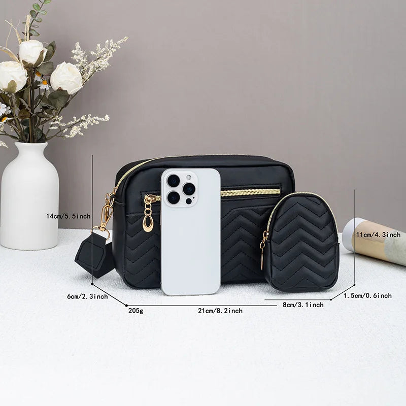 Eine schwarze gesteppte Crossbody-Tasche wird neben einem weißen iPhone und einer Blumenvase präsentiert.