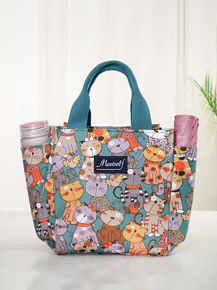 Bolsa bento de tela colorida con gatos y animales de dibujos animados, tapa rosa y asas verde azulado.