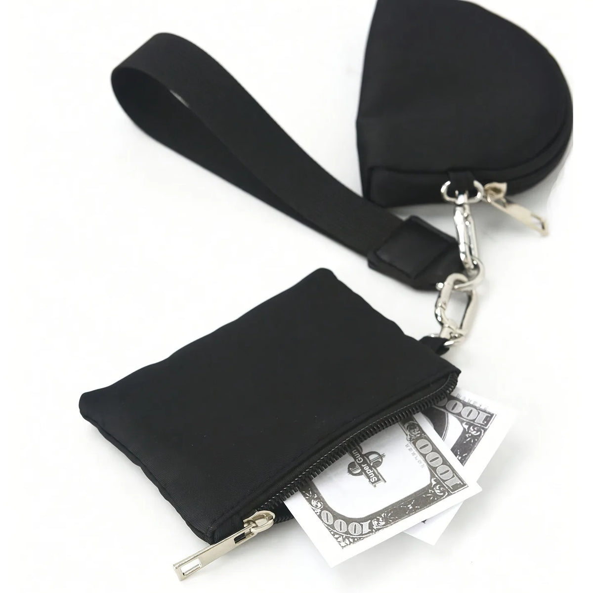 Black compact wristlet wallet with dual zip pockets and a leather strap, shown next to cash.