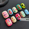 A collection of colorful, cartoon-themed press-on nails in various bright and pastel shades arranged on a dark surface.