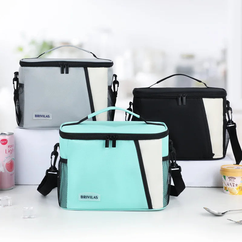 Three insulated reusable lunch bags in gray, black, and mint green are displayed on a white surface.