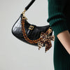 Schwarze Alligatormuster-Acryl-Tasche mit goldener Kette und Leopardenmuster-Schleif-Anhänger.