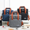 A gray insulated double-layer lunch bag with orange straps is displayed on a white surface.
