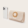 A woven straw envelope clutch with a round detail and detachable strap resting on a light background.