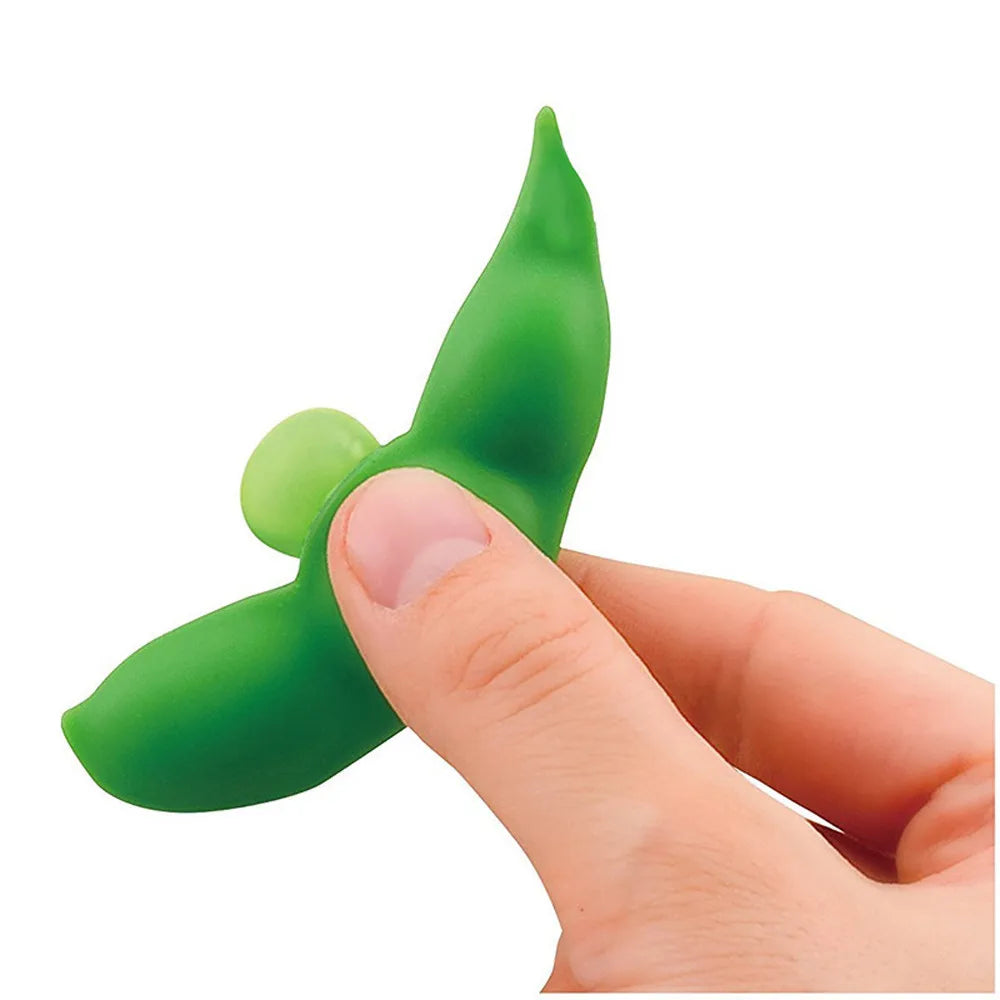 A hand is holding a bright green stress relief fidget toy keychain with a curved, leaf-like shape.