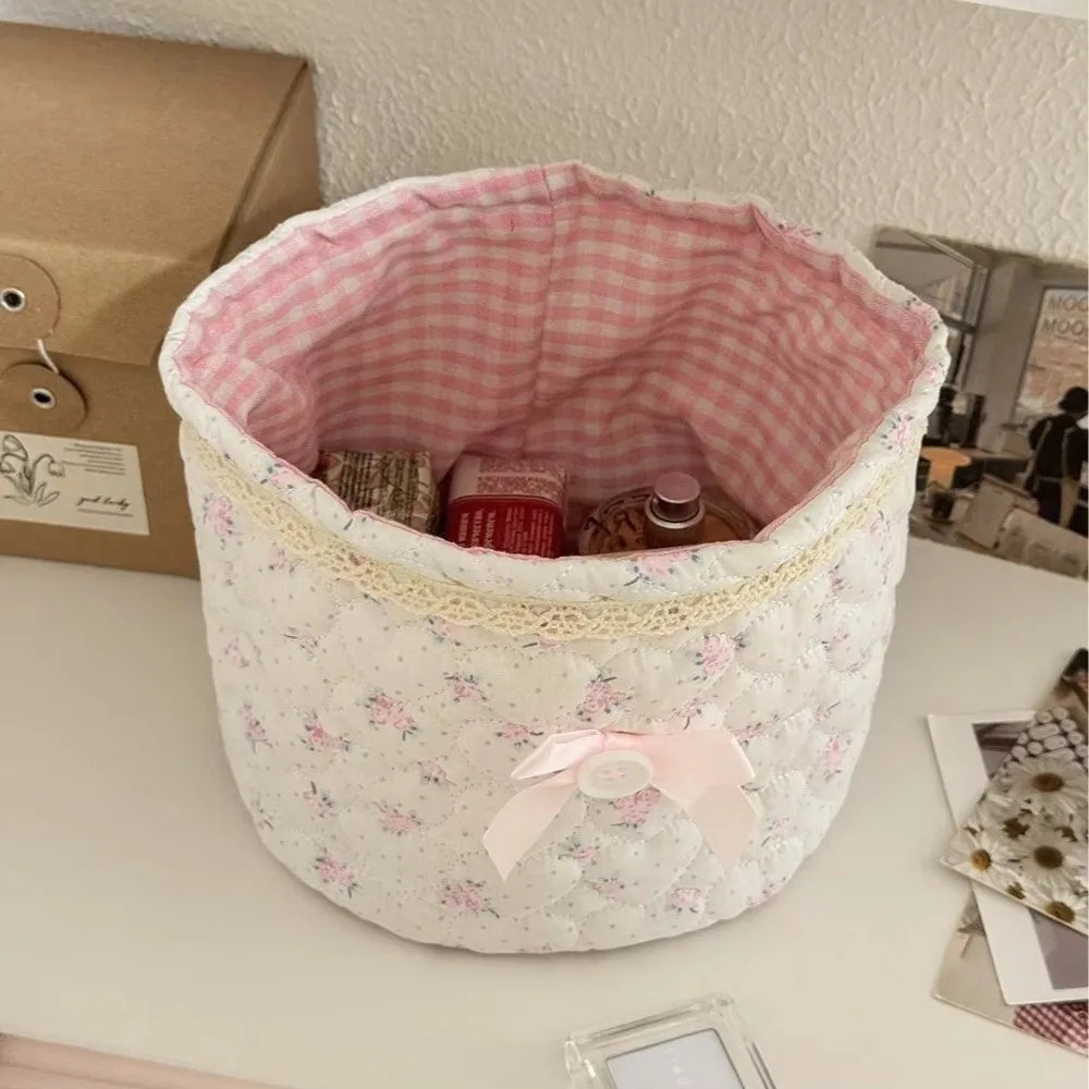 Cesta de almacenamiento de corazón acolchada de algodón blanco con forro a cuadros rosa y un lazo rosa en la parte superior.