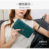 A woman holds a dark green RFID anti-theft multi-card wallet with a leather wrist strap.
