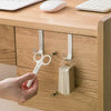 A hand is using a white hook rack to open a cabinet door, showing the multi-purpose hook rack for cabinet doors.