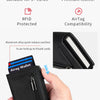 A hand holds a black minimalist magnetic wallet with a zipper, demonstrating its RFID protection and leather quality.