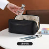 A black foldable cosmetic storage bag is shown open next to a hand pouring liquid into a glass bottle.