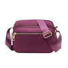 A deep purple compact oxford fabric crossbody bag with a gold-toned zipper and strap.