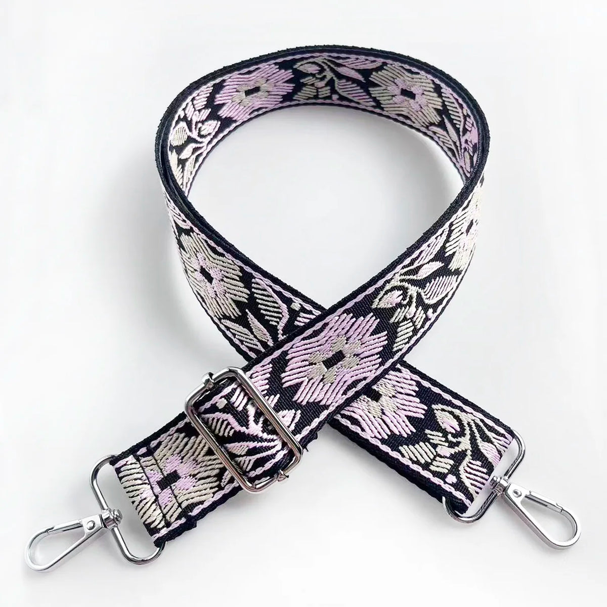A black and pink floral patterned adjustable strap for a crossbody bag.